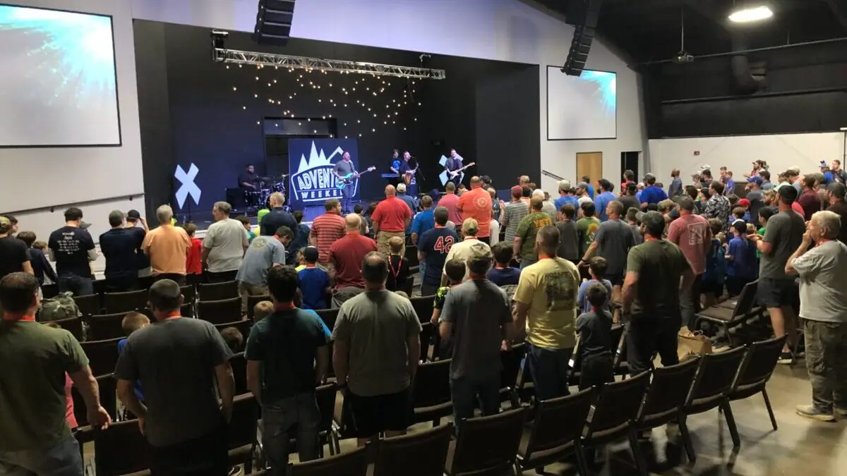 Fathers and sons worship together in large auditorium with band playing on stage