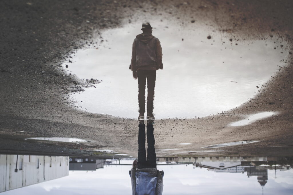 Upside down reflection in a puddle of a man standing
