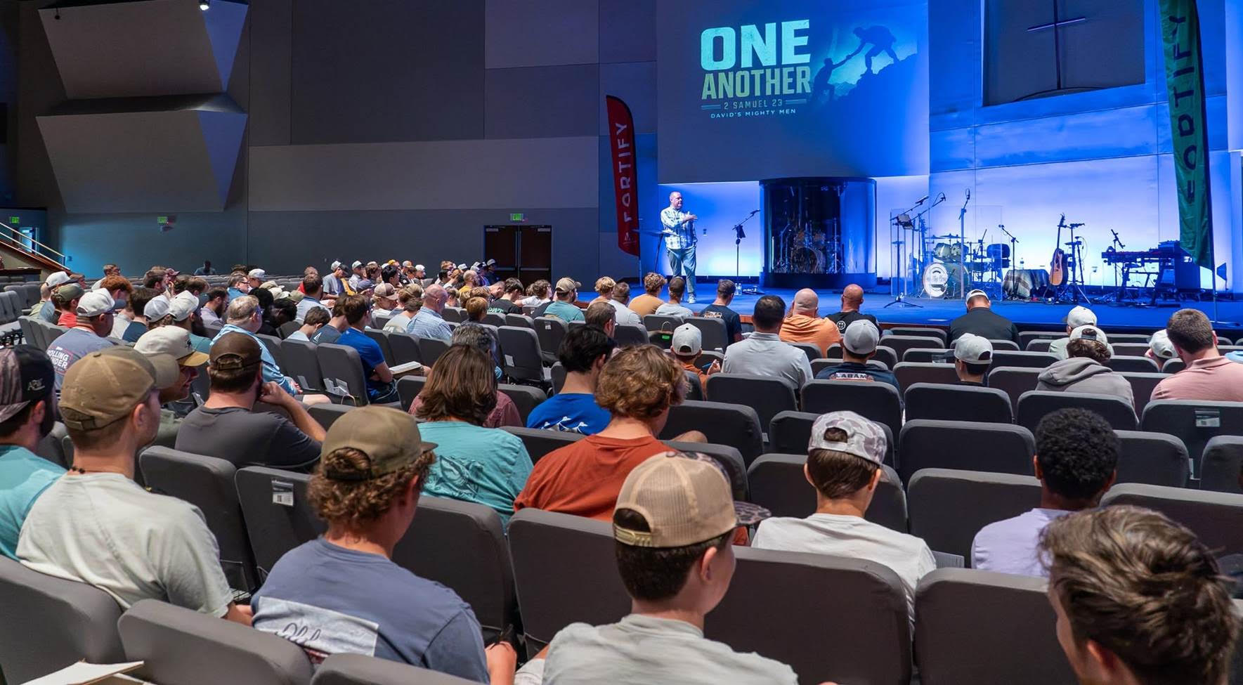 Daniel Atkins stands on a stage in front of a room of teen guys at the Fortify Conference.