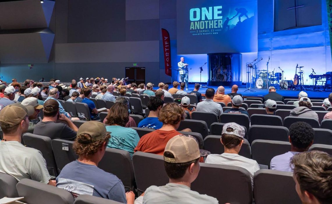 Daniel Atkins stands on a stage in front of a room of teen guys at the Fortify Conference.