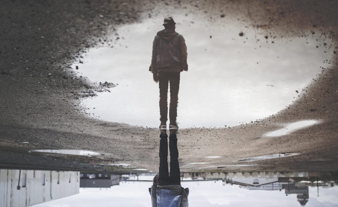 Upside down reflection in a puddle of a man standing